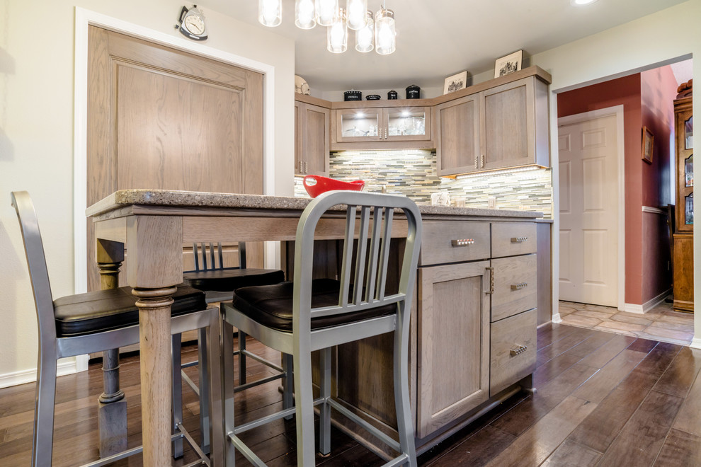 Inspiration for a mid-sized transitional u-shaped medium tone wood floor enclosed kitchen remodel in Miami with a farmhouse sink, shaker cabinets, gray cabinets, quartz countertops, gray backsplash, glass tile backsplash, white appliances and an island