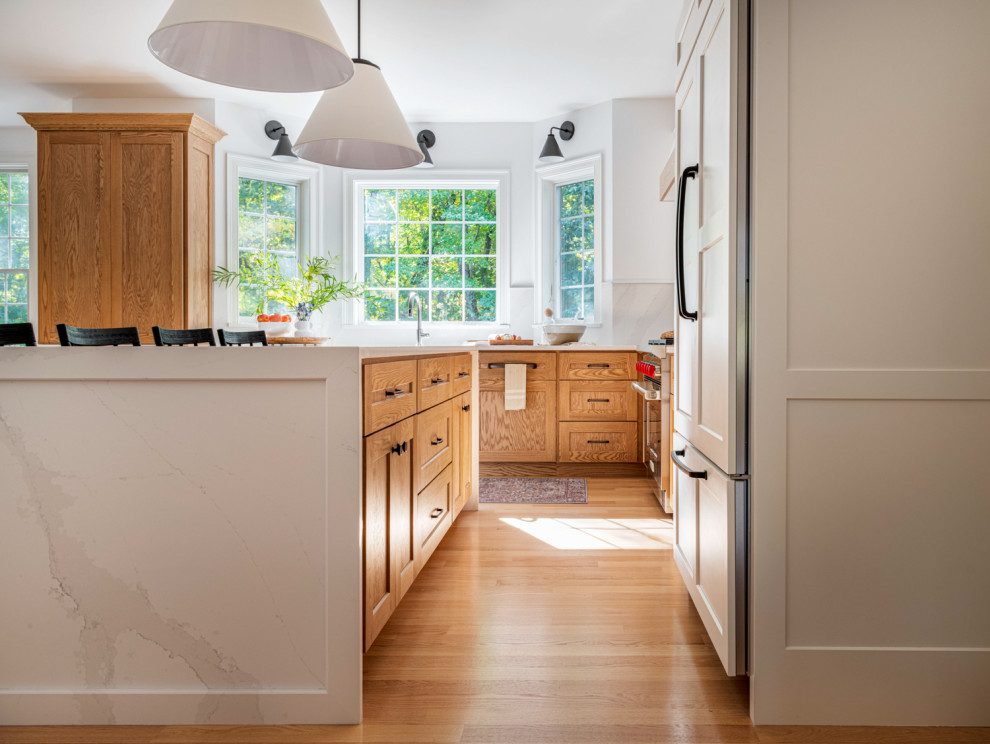 Eat-in kitchen - large transitional l-shaped light wood floor eat-in kitchen idea in Boston with an undermount sink, shaker cabinets, quartz countertops, white backsplash, quartz backsplash, stainless steel appliances, an island and white countertops