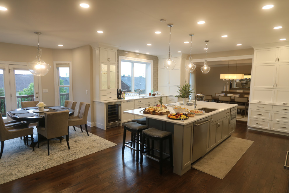 Eat-in kitchen - huge transitional u-shaped dark wood floor and brown floor eat-in kitchen idea in Cincinnati with an undermount sink, recessed-panel cabinets, white cabinets, quartz countertops, beige backsplash, subway tile backsplash, stainless steel appliances, an island and white countertops