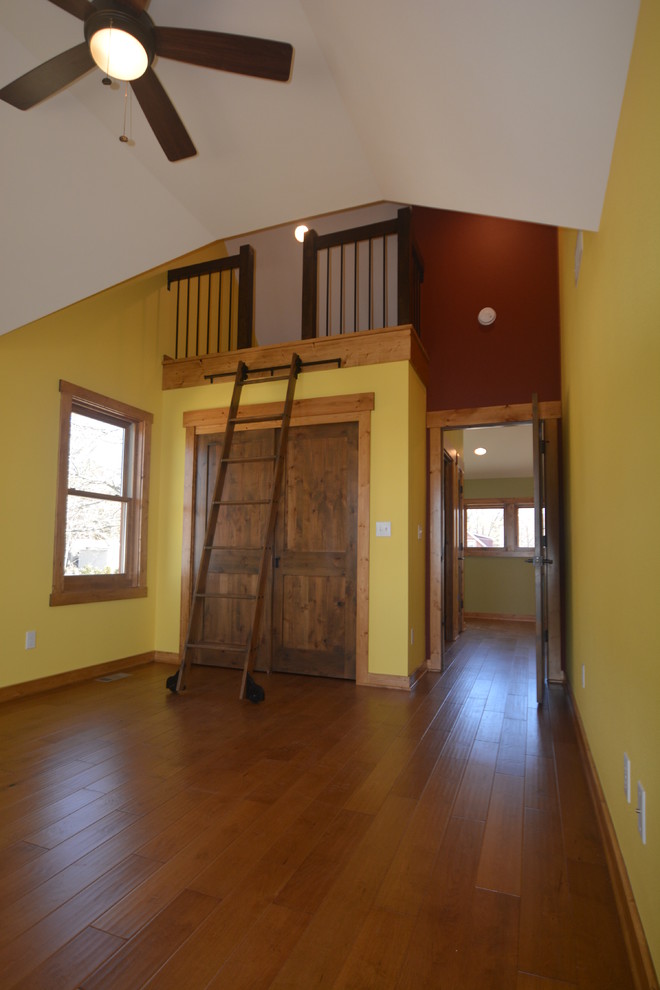 Mid-sized arts and crafts loft-style bedroom in Milwaukee with multi-coloured walls, medium hardwood floors and brown floor.