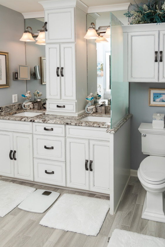Small beach style master bathroom in Atlanta with recessed-panel cabinets, a drop-in tub, blue walls, porcelain floors, an undermount sink, granite benchtops and grey floor.