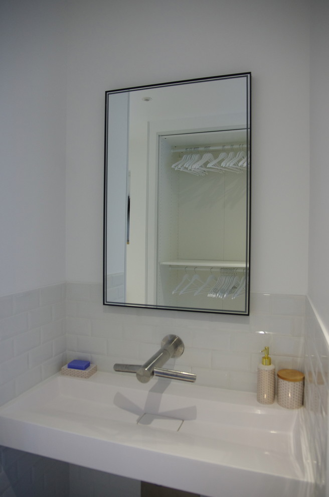 This is an example of a mid-sized contemporary powder room in Paris with white walls, a wall-mount sink, white tile, subway tile, cement tiles, blue floor and white benchtops.