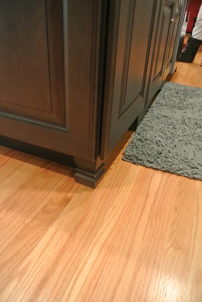 Example of a large transitional l-shaped light wood floor eat-in kitchen design in Boston with a farmhouse sink, shaker cabinets, gray cabinets, granite countertops, white backsplash, ceramic backsplash, stainless steel appliances, an island and gray countertops