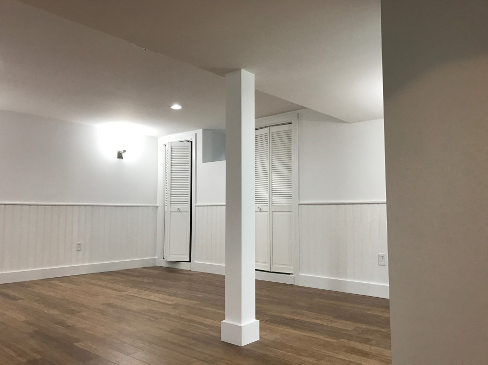 Photo of a mid-sized contemporary fully buried basement in Boston with a home bar, bamboo floors, a plaster fireplace surround and decorative wall panelling.