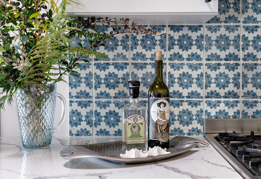 Example of a mid-sized mountain style brown floor and vaulted ceiling open concept kitchen design in Seattle with a farmhouse sink, shaker cabinets, quartz countertops, blue backsplash, ceramic backsplash, colored appliances and white countertops