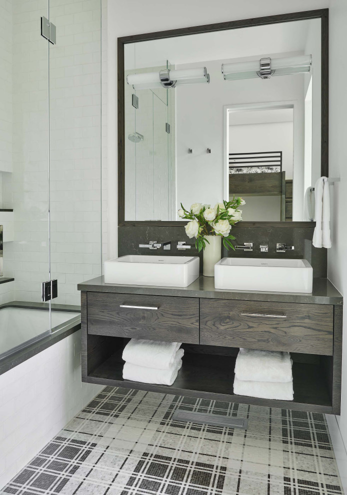 Modernes Badezimmer mit flächenbündigen Schrankfronten, dunklen Holzschränken, Badewanne in Nische, Duschbadewanne, weißen Fliesen, weißer Wandfarbe, Aufsatzwaschbecken, buntem Boden, grauer Waschtischplatte, Doppelwaschbecken und schwebendem Waschtisch in Denver