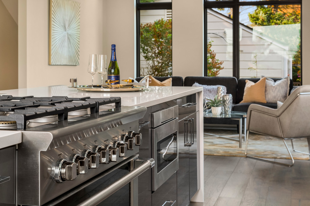 Inspiration for a mid-sized contemporary galley medium tone wood floor and brown floor open concept kitchen remodel in Los Angeles with an undermount sink, flat-panel cabinets, white cabinets, solid surface countertops, gray backsplash, matchstick tile backsplash, stainless steel appliances and an island