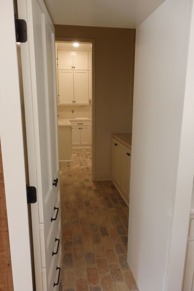 Photo of a mid-sized transitional hallway in Jackson with brick floors and beige walls.