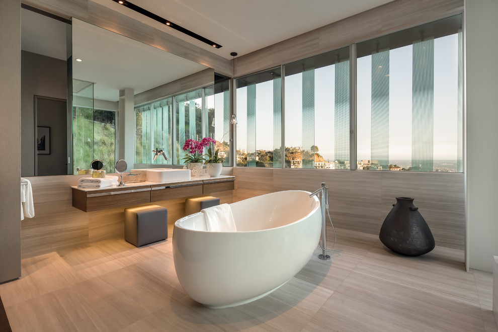 Freestanding bathtub - contemporary gray tile gray floor freestanding bathtub idea in Los Angeles with flat-panel cabinets, medium tone wood cabinets, gray walls, a vessel sink and white countertops