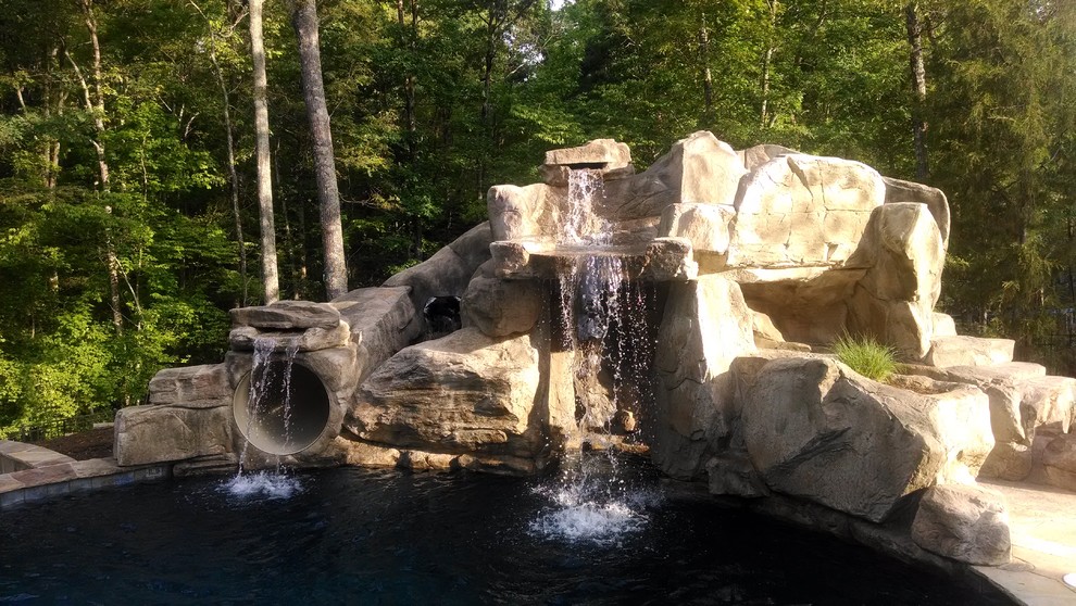 Inspiration for a large contemporary backyard custom-shaped pool in Charlotte with natural stone pavers and a water slide.