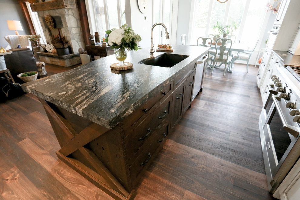 Open concept kitchen - large rustic l-shaped dark wood floor and brown floor open concept kitchen idea in Toronto with an undermount sink, recessed-panel cabinets, white cabinets, beige backsplash, glass tile backsplash, stainless steel appliances, an island, onyx countertops and black countertops