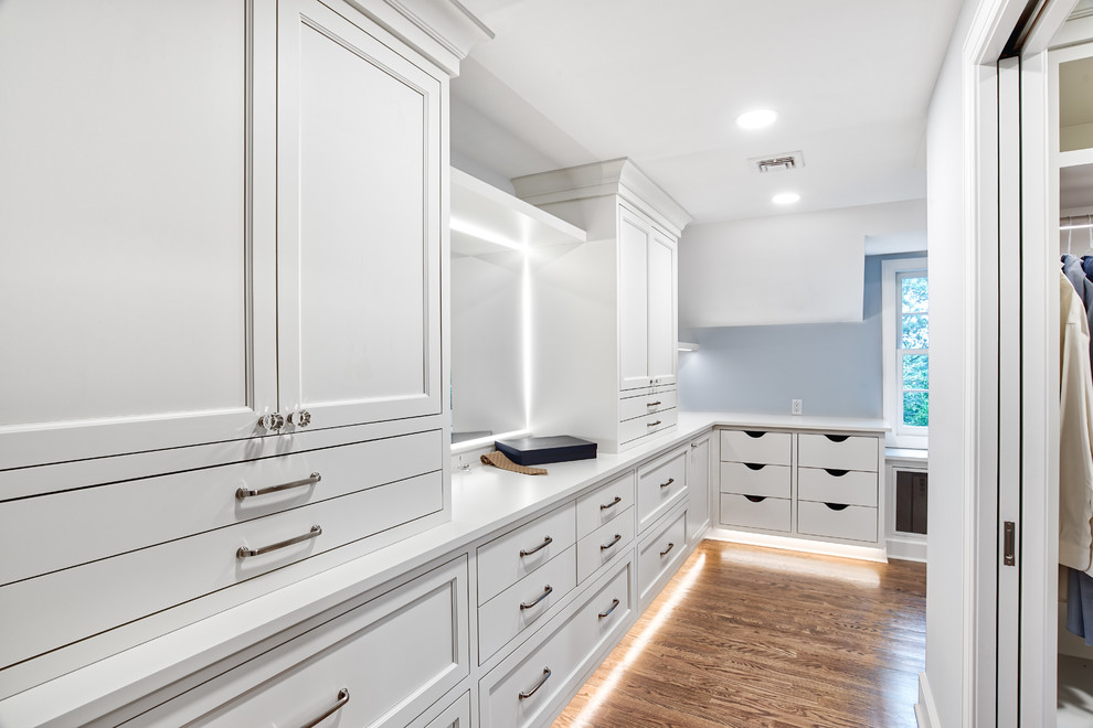 Expansive traditional women's walk-in wardrobe in New York with beaded inset cabinets, white cabinets and medium hardwood floors.