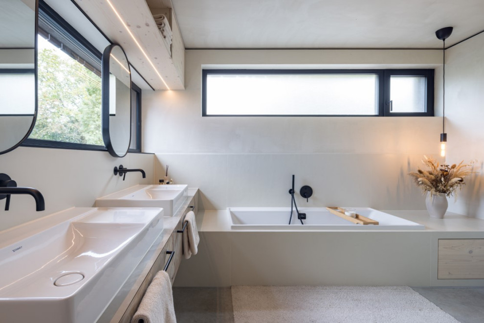Imagen de cuarto de baño doble moderno con bañera encastrada, ducha a ras de suelo, sanitario de pared, suelo de cemento, encimera de cemento, suelo gris y encimeras grises