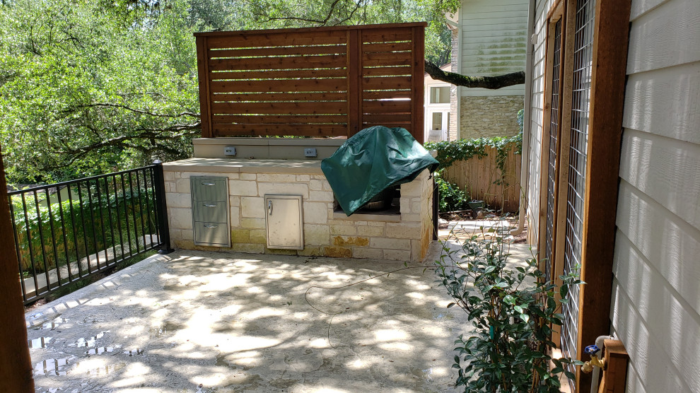 This is an example of a large eclectic backyard patio in Austin with an outdoor kitchen, concrete slab and a roof extension.