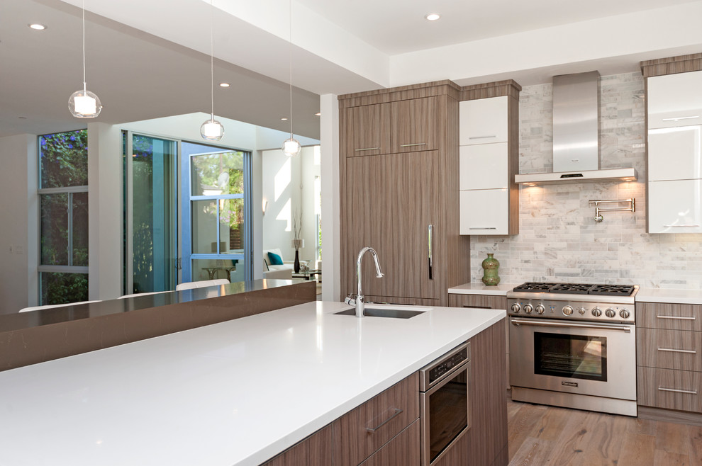 Inspiration for a mid-sized transitional l-shaped medium tone wood floor enclosed kitchen remodel in New York with an undermount sink, flat-panel cabinets, white cabinets, granite countertops, multicolored backsplash, ceramic backsplash, stainless steel appliances and an island
