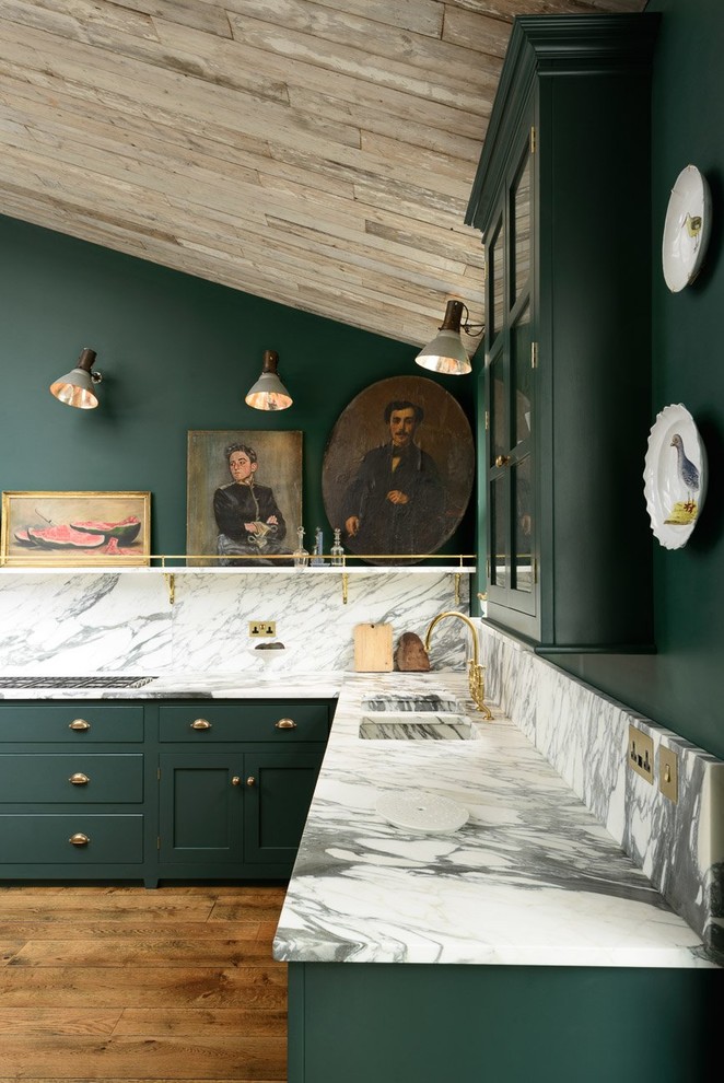 Mid-sized traditional l-shaped eat-in kitchen in London with a double-bowl sink, shaker cabinets, green cabinets, marble benchtops, stone slab splashback, black appliances, light hardwood floors and no island.