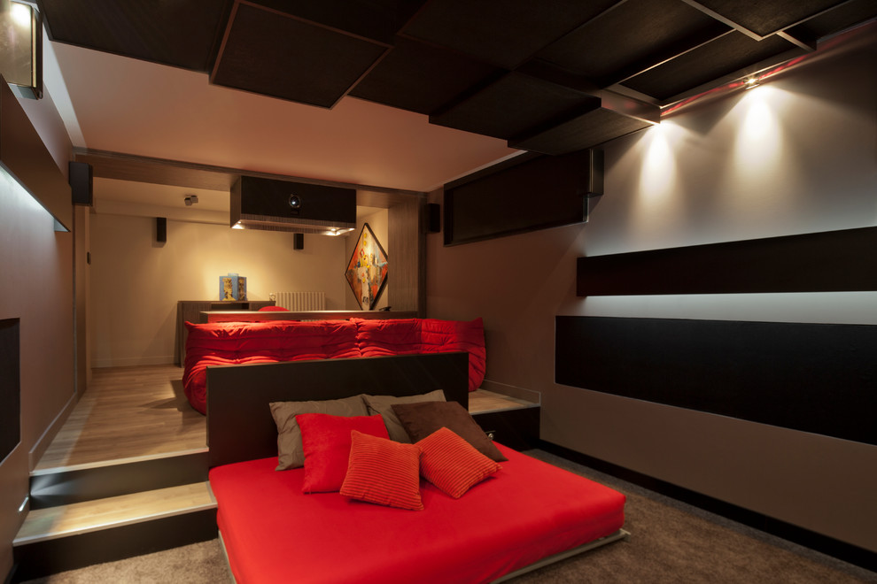 This is an example of a large contemporary enclosed home theatre in Lyon with beige walls, carpet, a projector screen and brown floor.
