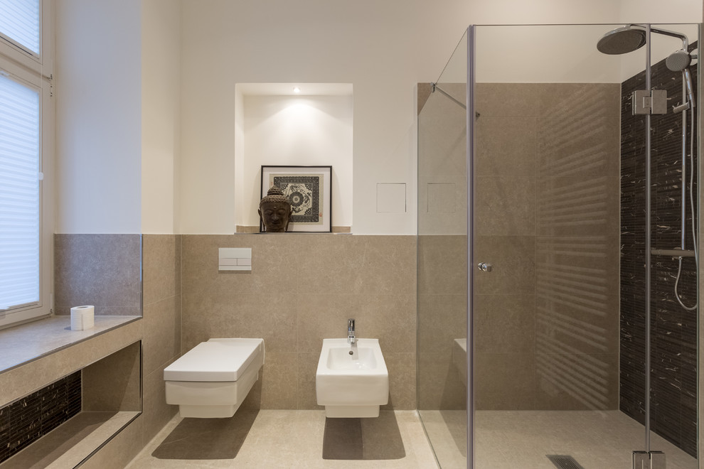 This is an example of a contemporary bathroom in Berlin with a drop-in tub, a curbless shower, a wall-mount toilet, beige tile, matchstick tile, beige walls, ceramic floors, a console sink, solid surface benchtops, beige floor and a hinged shower door.