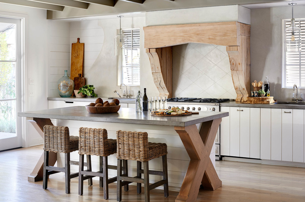 Design ideas for a country single-wall kitchen in Charlotte with with island, white cabinets, concrete benchtops, beige splashback, stainless steel appliances and light hardwood floors.