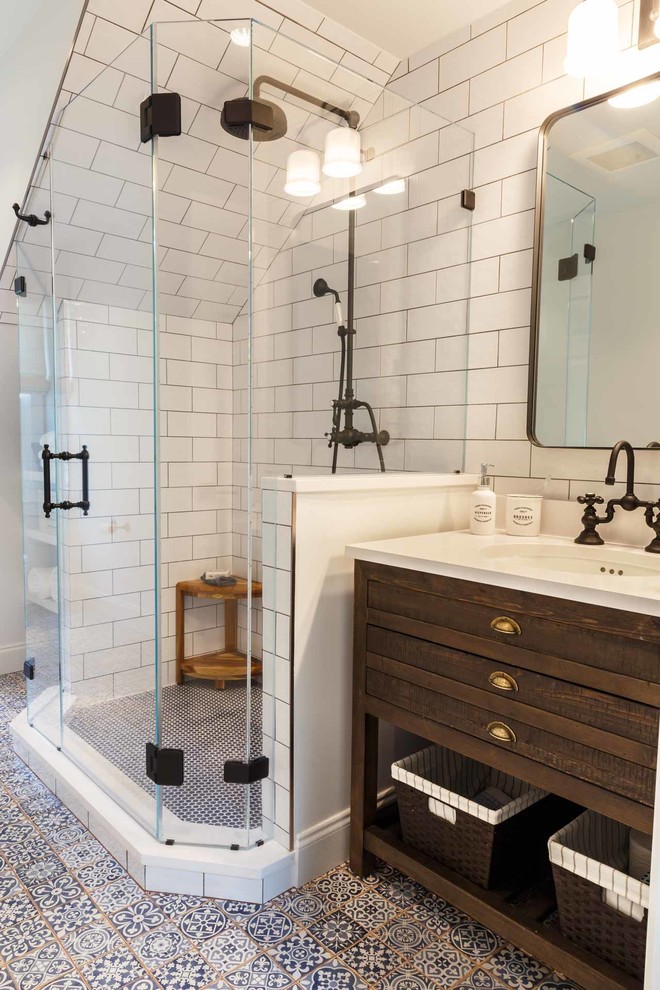 This is an example of a mid-sized industrial bathroom in DC Metro with brown cabinets, a corner shower, white tile, white walls, an undermount sink, blue floor, a hinged shower door and white benchtops.