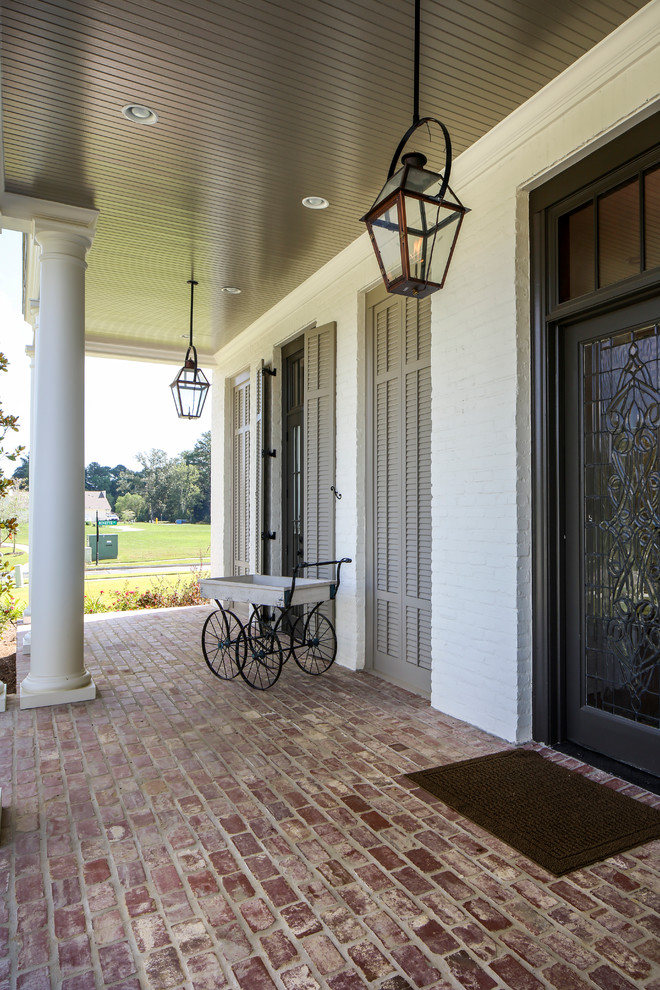 Design ideas for an expansive traditional front yard verandah in New Orleans with brick pavers and a roof extension.