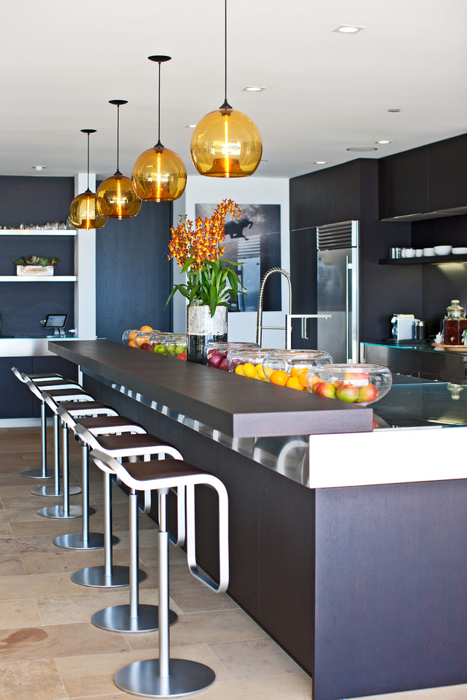 This is an example of a large contemporary l-shaped eat-in kitchen in Los Angeles with a drop-in sink, flat-panel cabinets, dark wood cabinets, stainless steel benchtops, stainless steel appliances, travertine floors, with island and beige floor.
