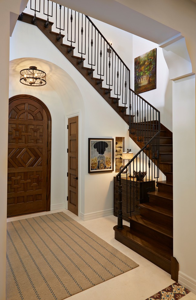 Inspiration for a mid-sized mediterranean foyer in Tampa with white walls, a single front door, a medium wood front door, beige floor and ceramic floors.