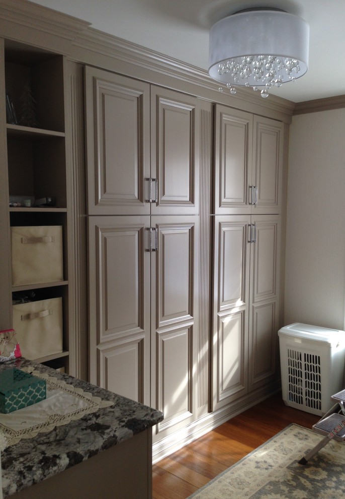 This is an example of a mid-sized traditional women's dressing room in New York with raised-panel cabinets, grey cabinets and medium hardwood floors.
