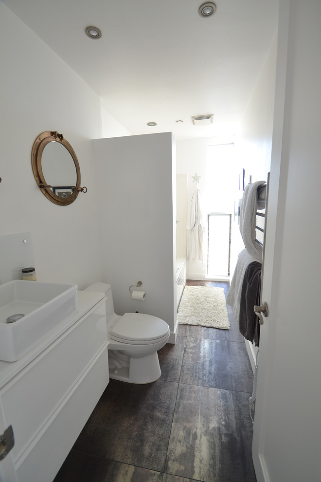This is an example of a mid-sized beach style 3/4 bathroom in San Diego with flat-panel cabinets, white cabinets, an alcove tub, an alcove shower, a one-piece toilet, black tile, porcelain tile, white walls and engineered quartz benchtops.