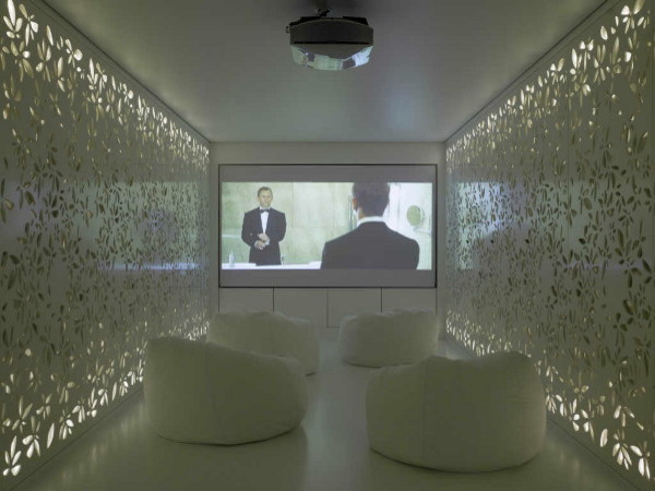 This is an example of a large modern enclosed home theatre in New York with white walls and a projector screen.