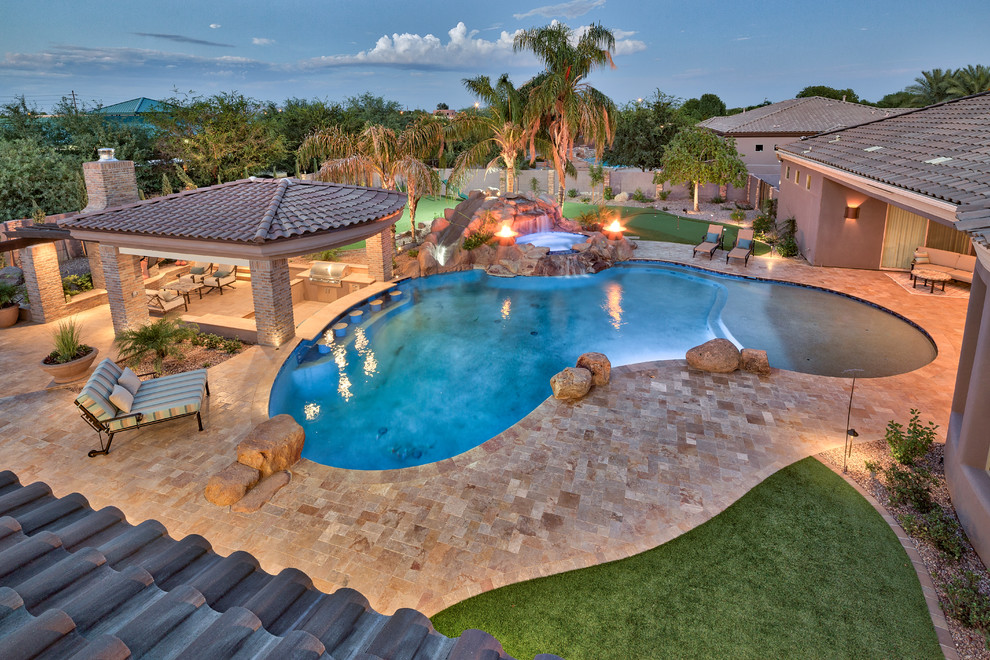 Photo of a large mediterranean backyard natural pool in Phoenix with natural stone pavers.