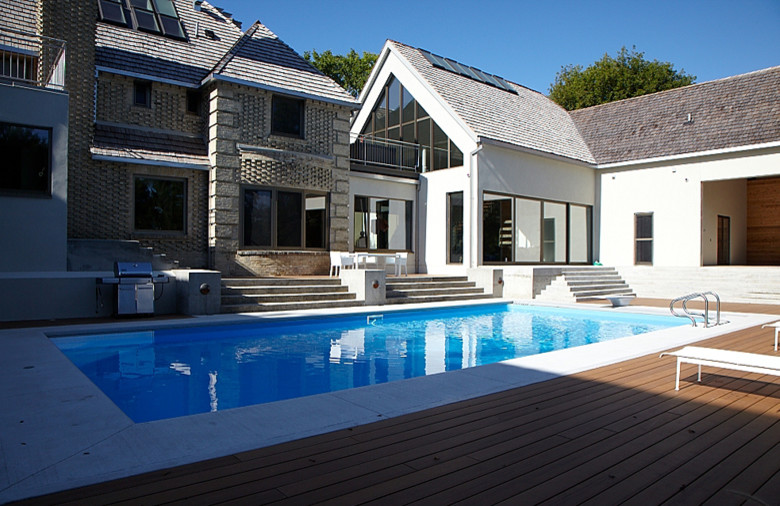 Example of a large minimalist backyard rectangular pool design with decking