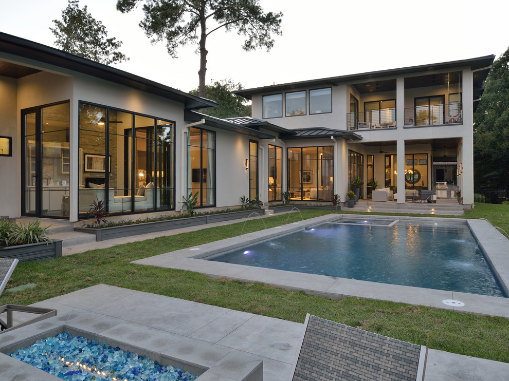 Design ideas for a large contemporary backyard rectangular lap pool in Houston with a water feature and concrete slab.