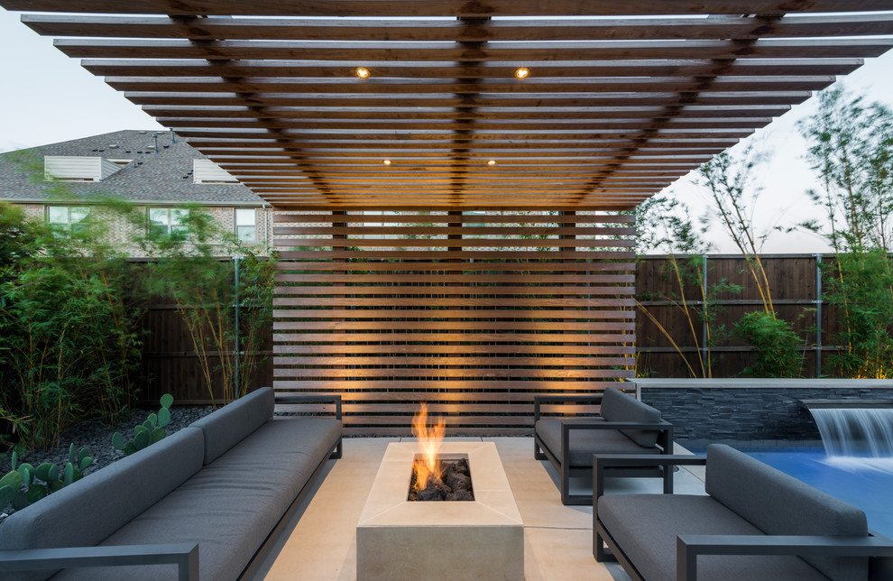 This is an example of a small contemporary backyard patio in Dallas with a fire feature, concrete slab and a pergola.
