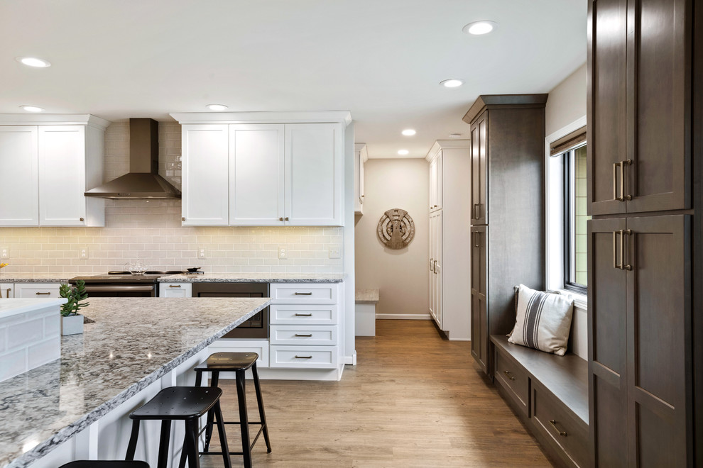 Eat-in kitchen - mid-sized transitional galley brown floor eat-in kitchen idea with an undermount sink, shaker cabinets, white cabinets, quartz countertops, ceramic backsplash and black appliances