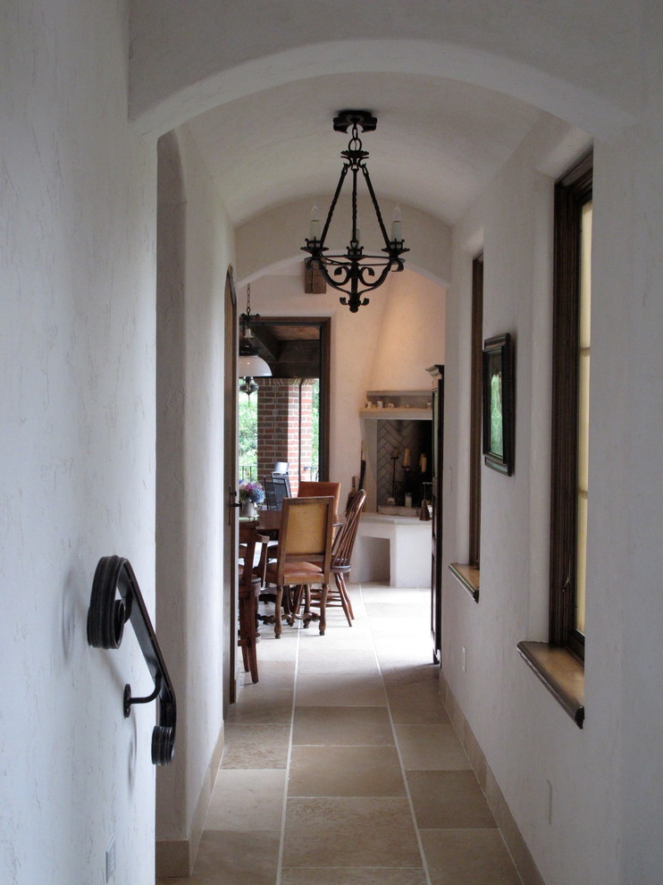 This is an example of a mid-sized mediterranean hallway in New York with white walls and limestone floors.