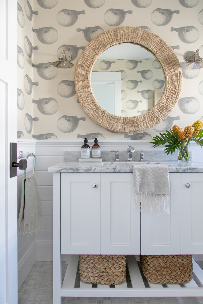 Large beach style powder room in New York with shaker cabinets, white cabinets, white walls, ceramic floors, an undermount sink, marble benchtops and beige floor.