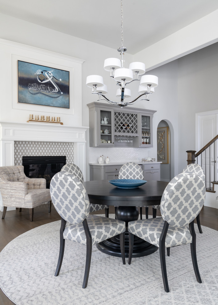 Design ideas for a medium sized traditional dining room in Dallas with grey walls, a standard fireplace, a tiled fireplace surround, brown floors, banquette seating and medium hardwood flooring.