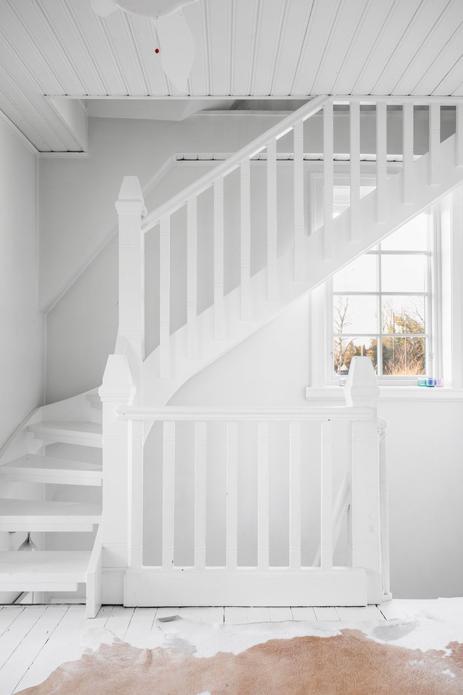 This is an example of a mid-sized country painted wood curved staircase in Malmo with open risers.