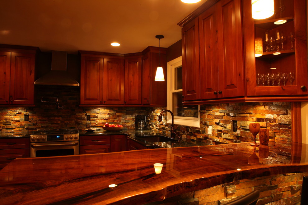 Eat-in kitchen - small rustic u-shaped eat-in kitchen idea with a single-bowl sink, raised-panel cabinets, medium tone wood cabinets, granite countertops, multicolored backsplash, stone slab backsplash, stainless steel appliances and no island