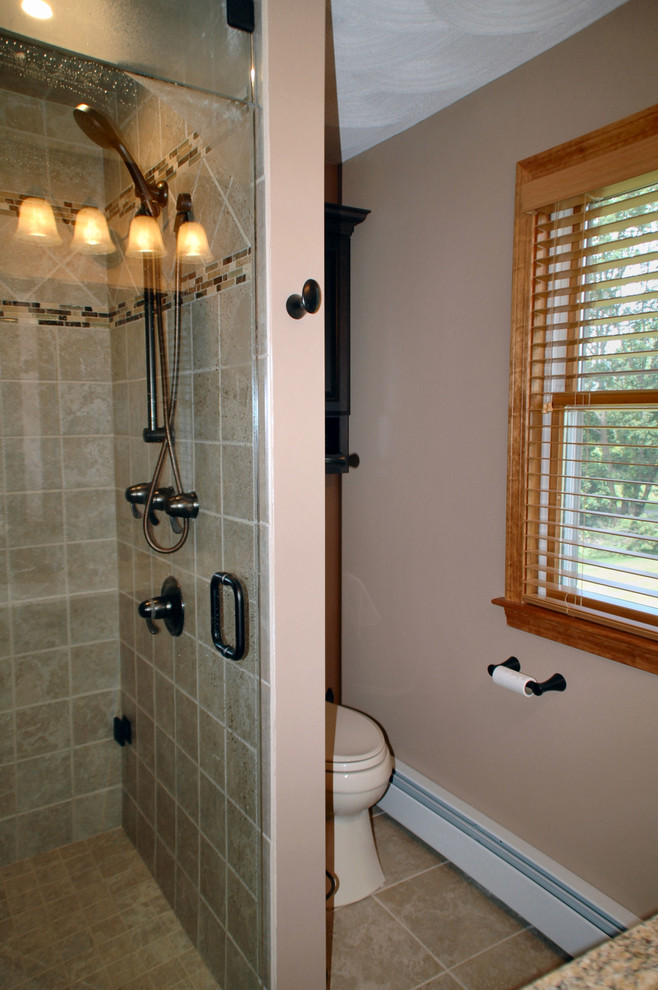 Mid-sized transitional master bathroom in Boston with raised-panel cabinets, dark wood cabinets, a corner shower, a two-piece toilet, beige tile, porcelain tile, white walls, porcelain floors, an undermount sink, granite benchtops, beige floor and a hinged shower door.
