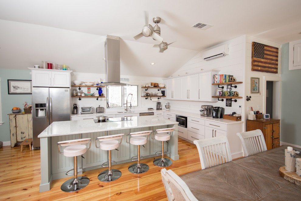 Photo of a mid-sized beach style l-shaped eat-in kitchen in Providence with an undermount sink, shaker cabinets, white cabinets, quartz benchtops, white splashback, timber splashback, stainless steel appliances, with island, medium hardwood floors and brown floor.