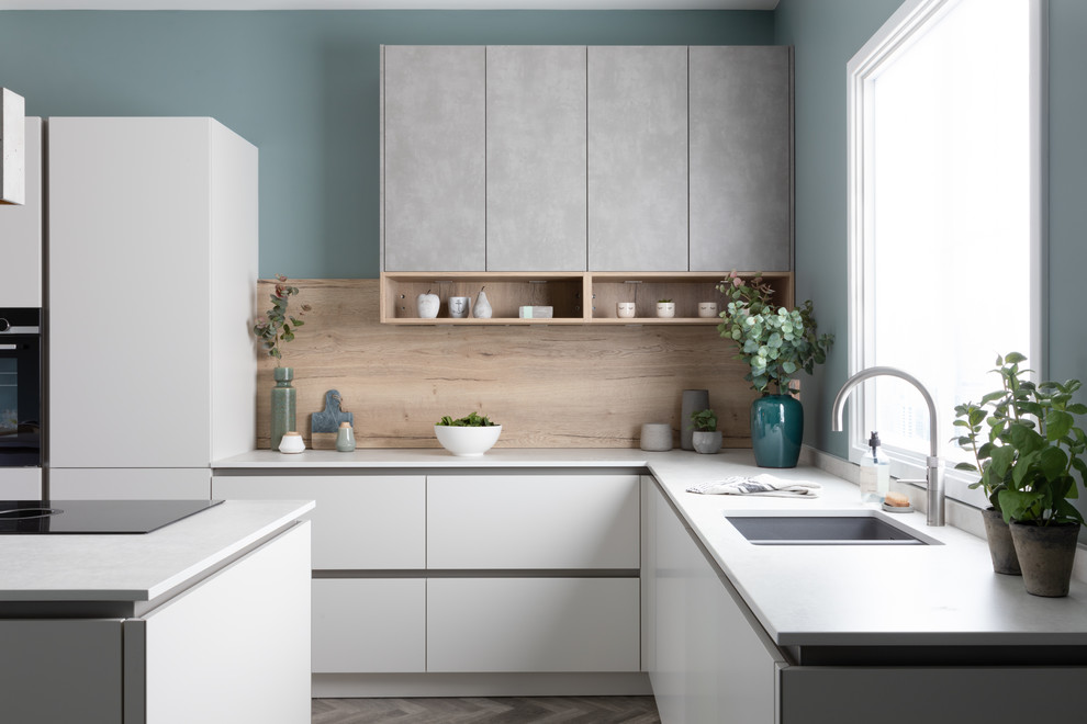 Mid-sized scandinavian u-shaped kitchen in West Midlands with an undermount sink, flat-panel cabinets, white cabinets, beige splashback, timber splashback, with island and white benchtop.