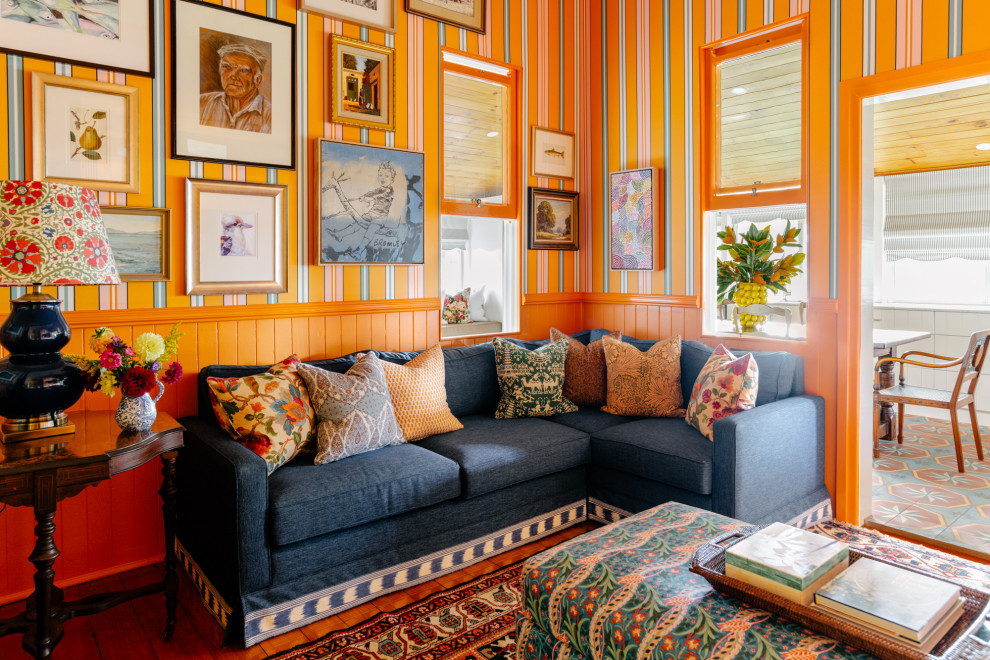 Abgetrenntes Country Wohnzimmer mit bunten Wänden, braunem Holzboden, braunem Boden, vertäfelten Wänden und Tapetenwänden in Brisbane