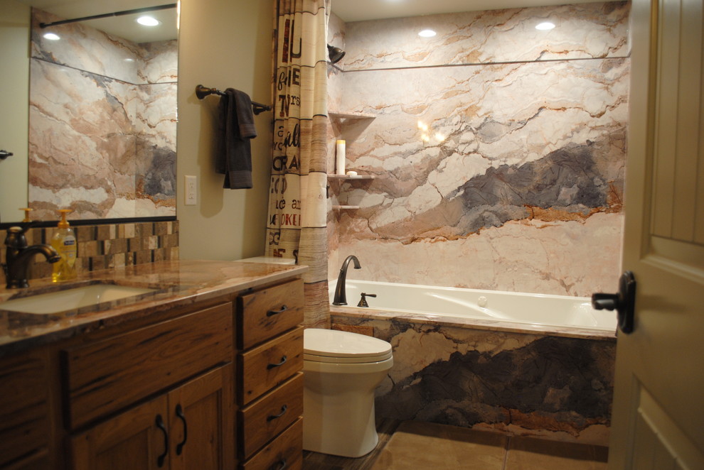 Inspiration for a small country bathroom in Other with recessed-panel cabinets, light wood cabinets, an alcove tub, an alcove shower, a two-piece toilet, multi-coloured tile, stone slab, beige walls, ceramic floors, an undermount sink, limestone benchtops, brown floor, a shower curtain and multi-coloured benchtops.