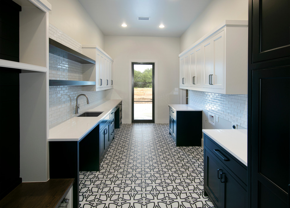 This is an example of a large traditional galley separated utility room in Dallas with a submerged sink, shaker cabinets, black cabinets, engineered stone countertops, white splashback, metro tiled splashback, white walls, ceramic flooring, a side by side washer and dryer, black floors and white worktops.