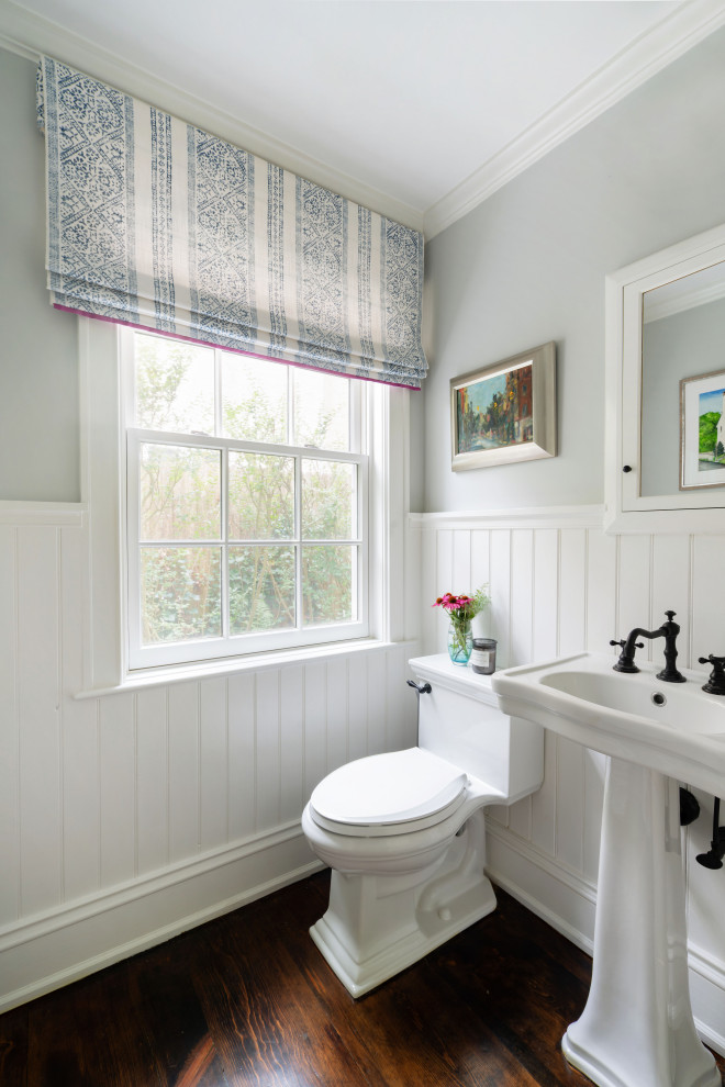 Design ideas for a traditional powder room in Philadelphia with white cabinets, grey walls, dark hardwood floors, a pedestal sink and panelled walls.