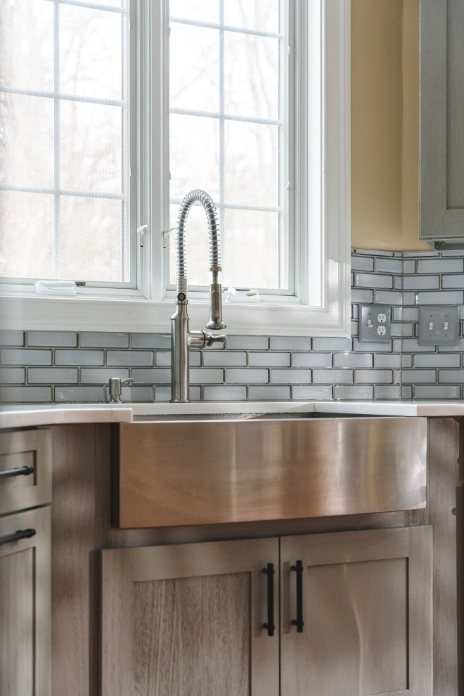 Inspiration for a large transitional u-shaped medium tone wood floor and brown floor eat-in kitchen remodel with a farmhouse sink, shaker cabinets, gray cabinets, quartz countertops, gray backsplash, glass tile backsplash, stainless steel appliances, an island and white countertops
