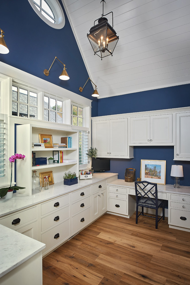 This is an example of a mid-sized beach style study room with blue walls, medium hardwood floors, a built-in desk and no fireplace.