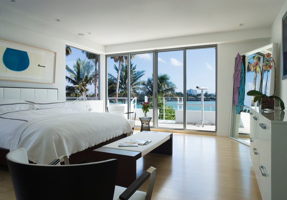 Large beach style master bedroom in Miami with white walls, light hardwood floors, no fireplace and beige floor.